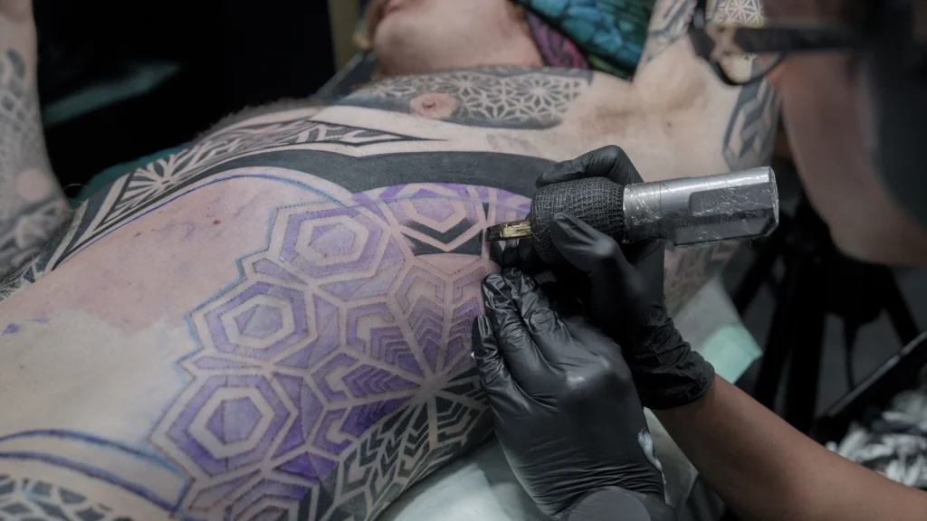 Tattoo artist working on a large body tattoo