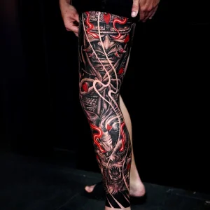 Japanese leg sleeve tattoo featuring a fierce samurai mask and red glowing accents.